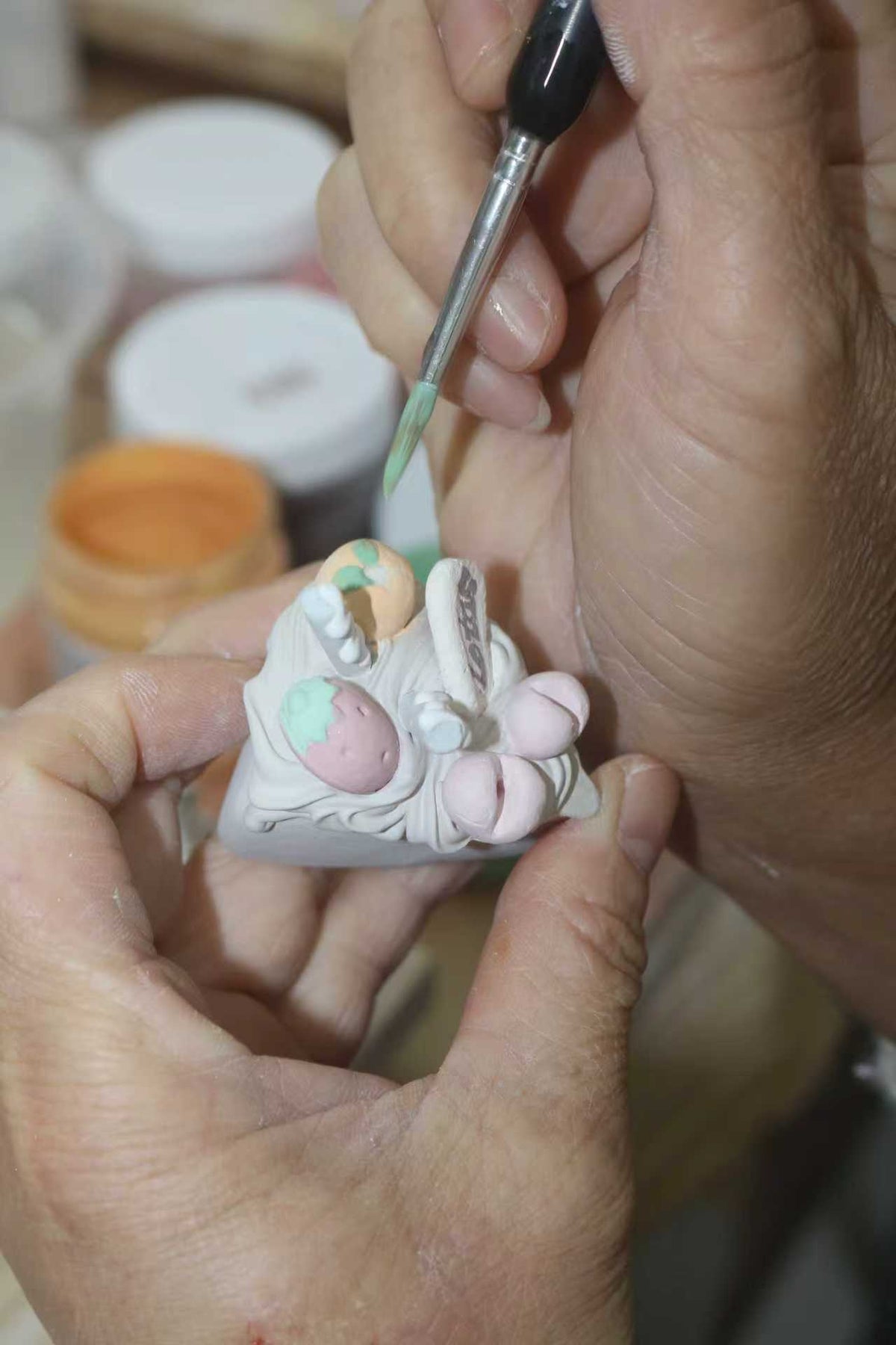 Working on the details of a ceramic cake with a fine brush