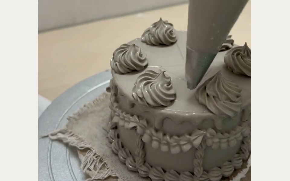 Piping clay by hand to form a ceramic cake